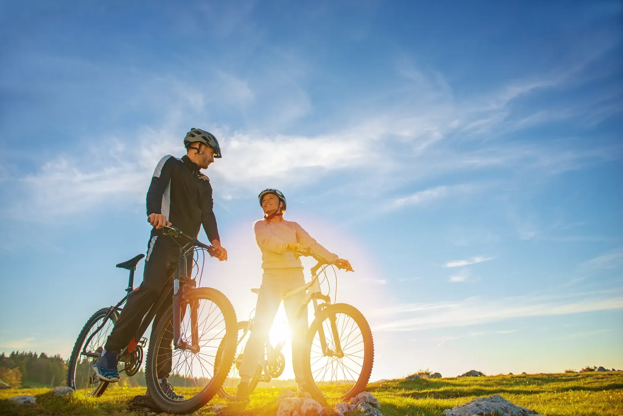 Landschaft mit zwei Personen und Fahrrädern, die sich unterhalten 2 Fahrradfahrer im Sonnenuntergang