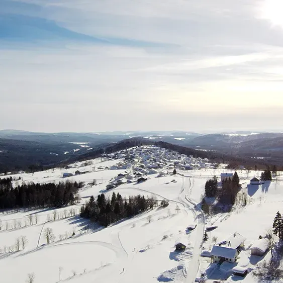 Blick auf Finsterau und strahlend weiße Winterwunderland mit verschneiten Erhebungen aus der Vogelperspektive